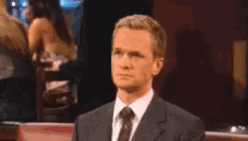 a man in a suit and tie is sitting at a table making a funny face .