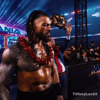 a man with a championship belt stands in front of a sign that says ' roman reigns '