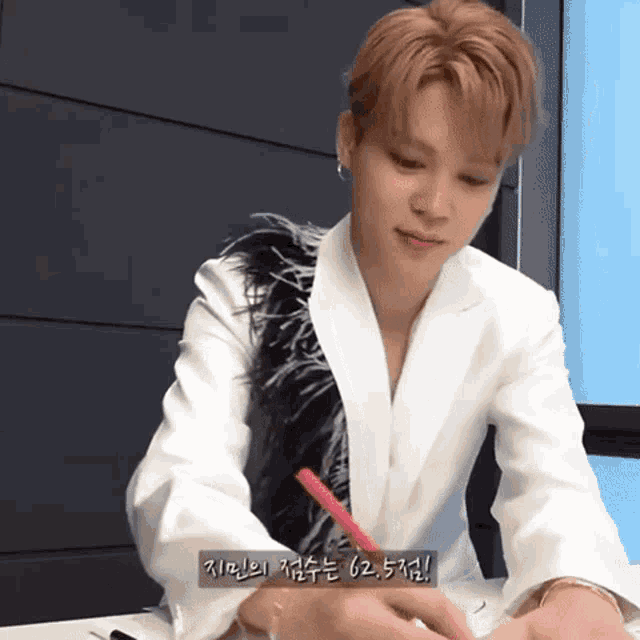 a man in a white jacket is writing on a piece of paper in korean