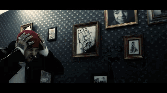 a man wearing a red hat stands in front of framed pictures