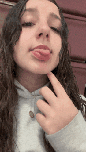 a girl sticking her tongue out while wearing a white sweatshirt