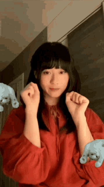 a girl in a red shirt is making a funny face with her hands