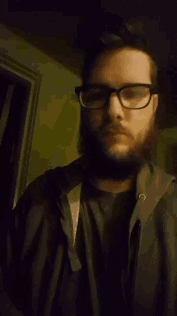 a man with glasses and a beard is making a middle finger gesture