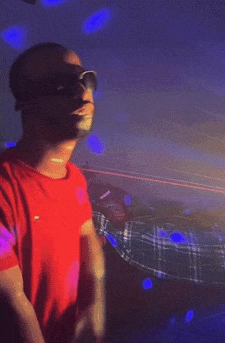 a man in a red shirt and sunglasses is dancing