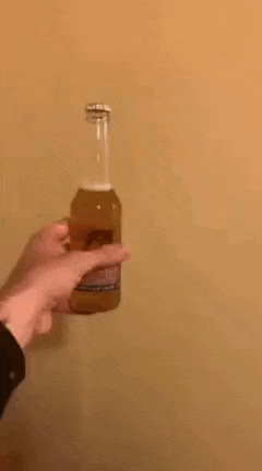 a person is opening a bottle of soda with their fingers .
