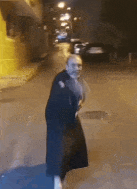 a man in a black robe is walking down a street .