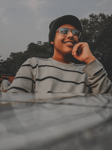 a young man wearing sunglasses and a hat smiles