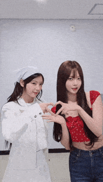 two girls are making a heart shape with their fingers