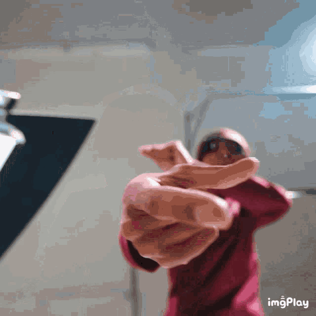 a person in a red hoodie is pointing at the camera with their fingers