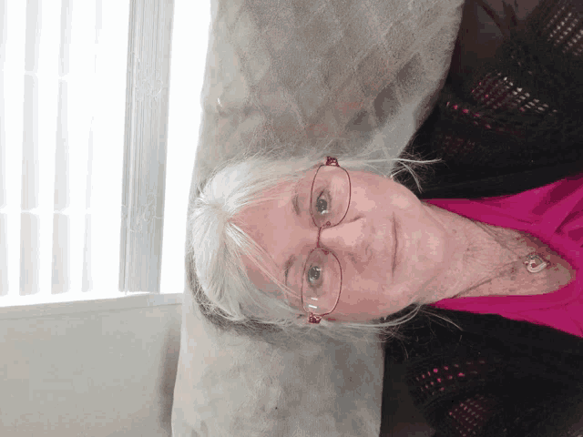 an older woman wearing glasses and a pink shirt