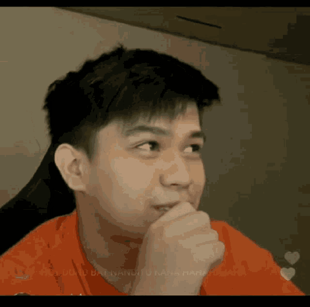 a man in an orange shirt has his hand to his mouth and the words hut duduk berbanditu kana rana rajaha on the bottom right