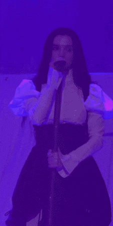 a woman is singing into a microphone in a blue light