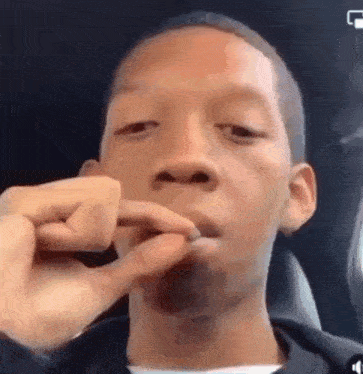 a young man is smoking a cigarette in a car while looking at the camera .