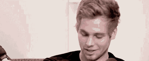 a young man with blonde hair is sitting in front of a microphone .