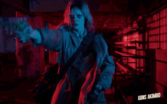 a woman in a blue coat is holding a gun with the words guns akimbc below her