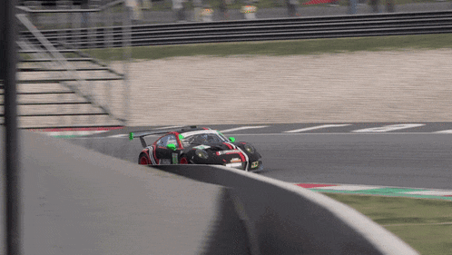 a race car with a green wing is going around a curve