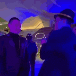 a blurry picture of a man in a hat talking to another man