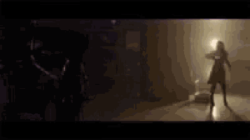 a blurry picture of a person standing in a dark room with a purple light coming out of the ceiling .