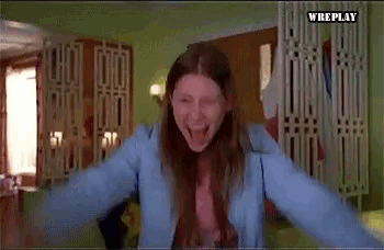 a woman in a blue jacket is screaming with her arms outstretched in a room with the words wreplay on the bottom