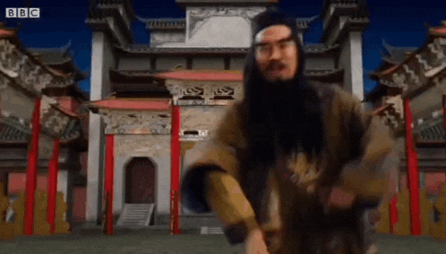 a man with a beard and glasses is dancing in front of a temple .