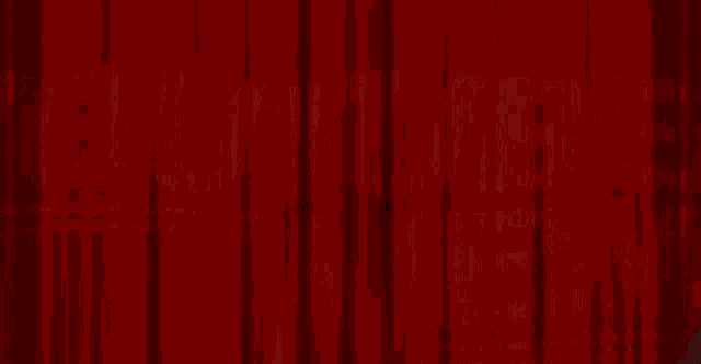 a man in a tuxedo is standing in front of a red curtain with his arms outstretched .