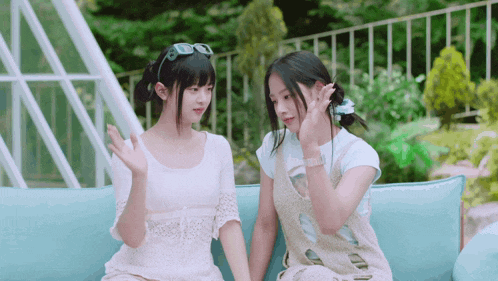two girls are sitting on a blue couch and talking to each other