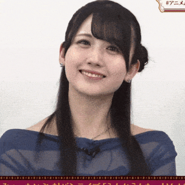 a woman wearing a blue off the shoulder top smiles for the camera