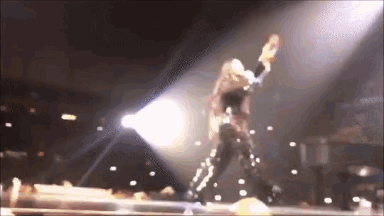 a woman is dancing on a stage in front of a crowd in a dark room