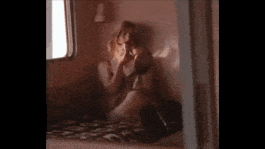 a woman sitting on a bed looking at herself in a mirror .