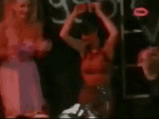 a group of women are dancing in a dark room in front of a neon sign that says ' a ' on it .