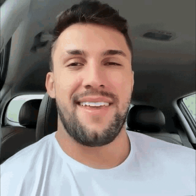 a man with a beard wearing a white shirt is smiling
