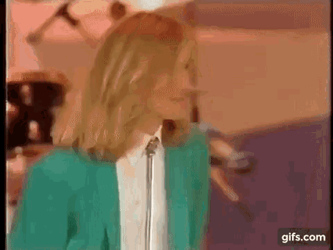 a woman in a green jacket is singing into a microphone