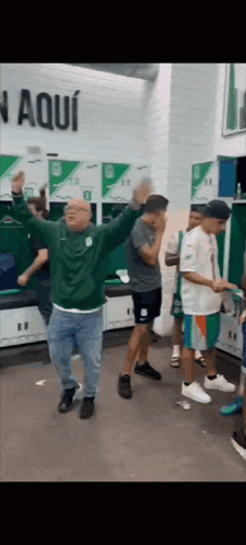 a group of people are dancing in a locker room with a sign that says n aqui