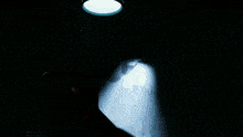 a man in a red shirt is standing in a dark room looking at a shadow .