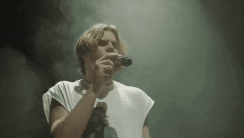 a man in a white shirt is singing into a microphone in a dark room