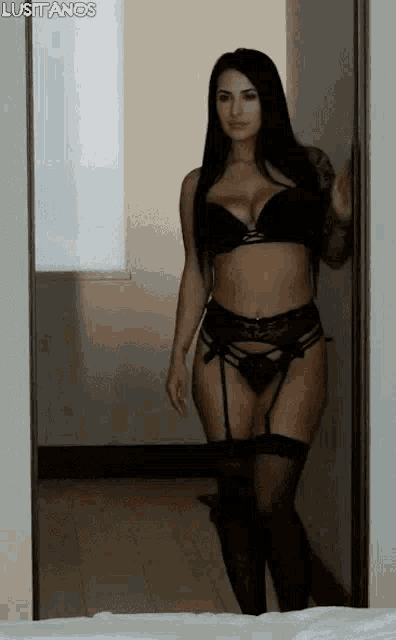 a woman in lingerie is standing in a doorway in front of a window .