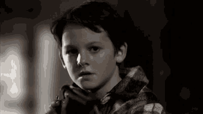 a young boy is holding a gun in his hand and looking at the camera .