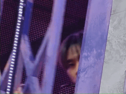a close up of a person 's face behind a purple wall .