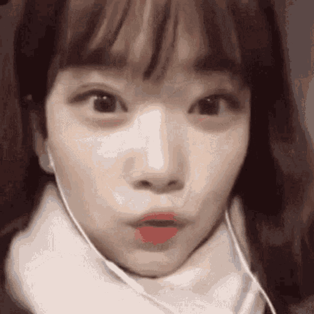 a close up of a girl wearing headphones and a scarf making a funny face .