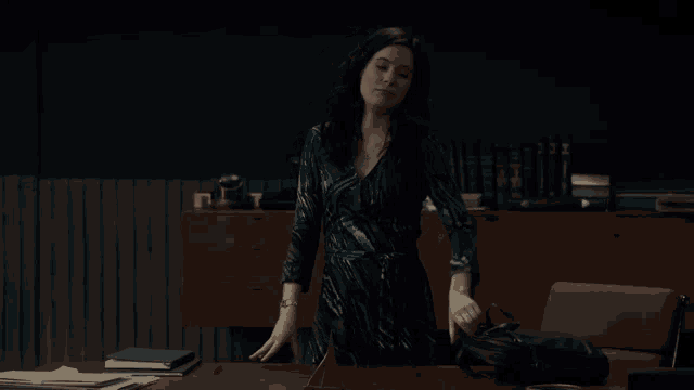 a woman in a blue dress is standing in front of a desk and says too bad