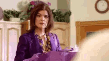 a woman in a purple suit is holding purple wrapping paper in a kitchen .