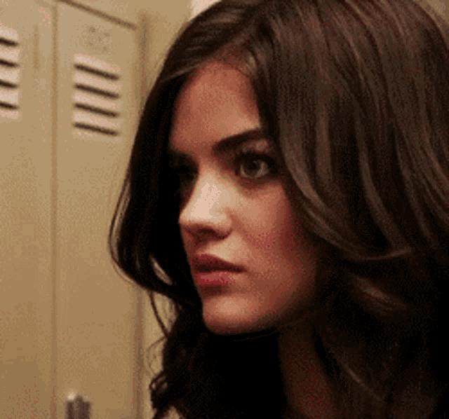 a close up of a woman 's face in front of a row of lockers