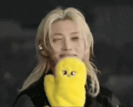a man with blonde hair is holding a yellow stuffed animal in his mouth .