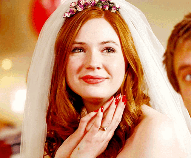 a woman with red hair wearing a veil and a ring