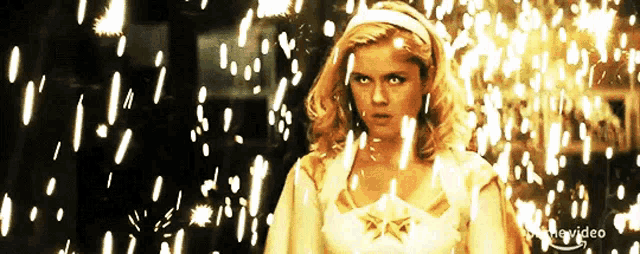 a woman in a white dress with a star on it is surrounded by sparks ..