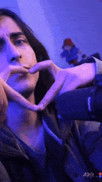 a man is making a heart shape with his hands .