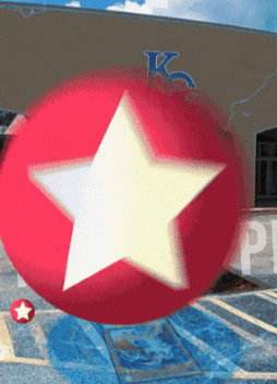 a red ball with a white star on it is in front of a building that says k on it