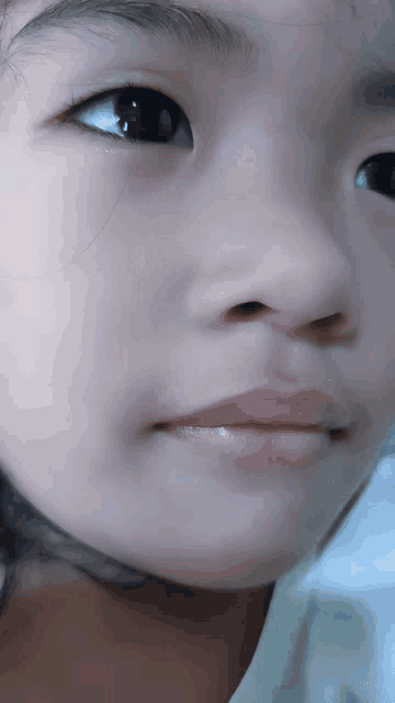 a close up of a child 's face with a white shirt