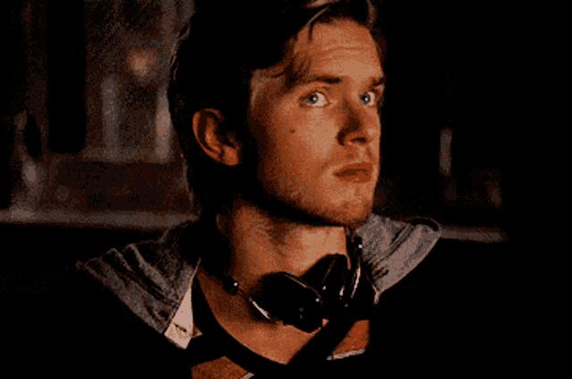 a man wearing headphones around his neck looks at something