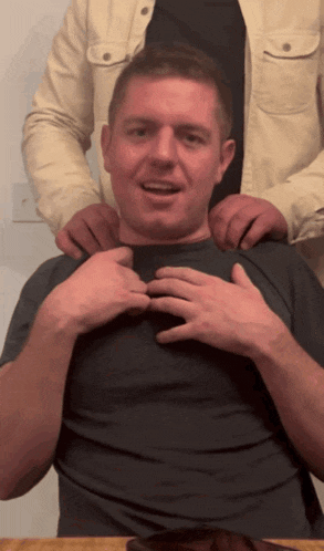 a man in a black shirt is being adjusted by another man in a white jacket